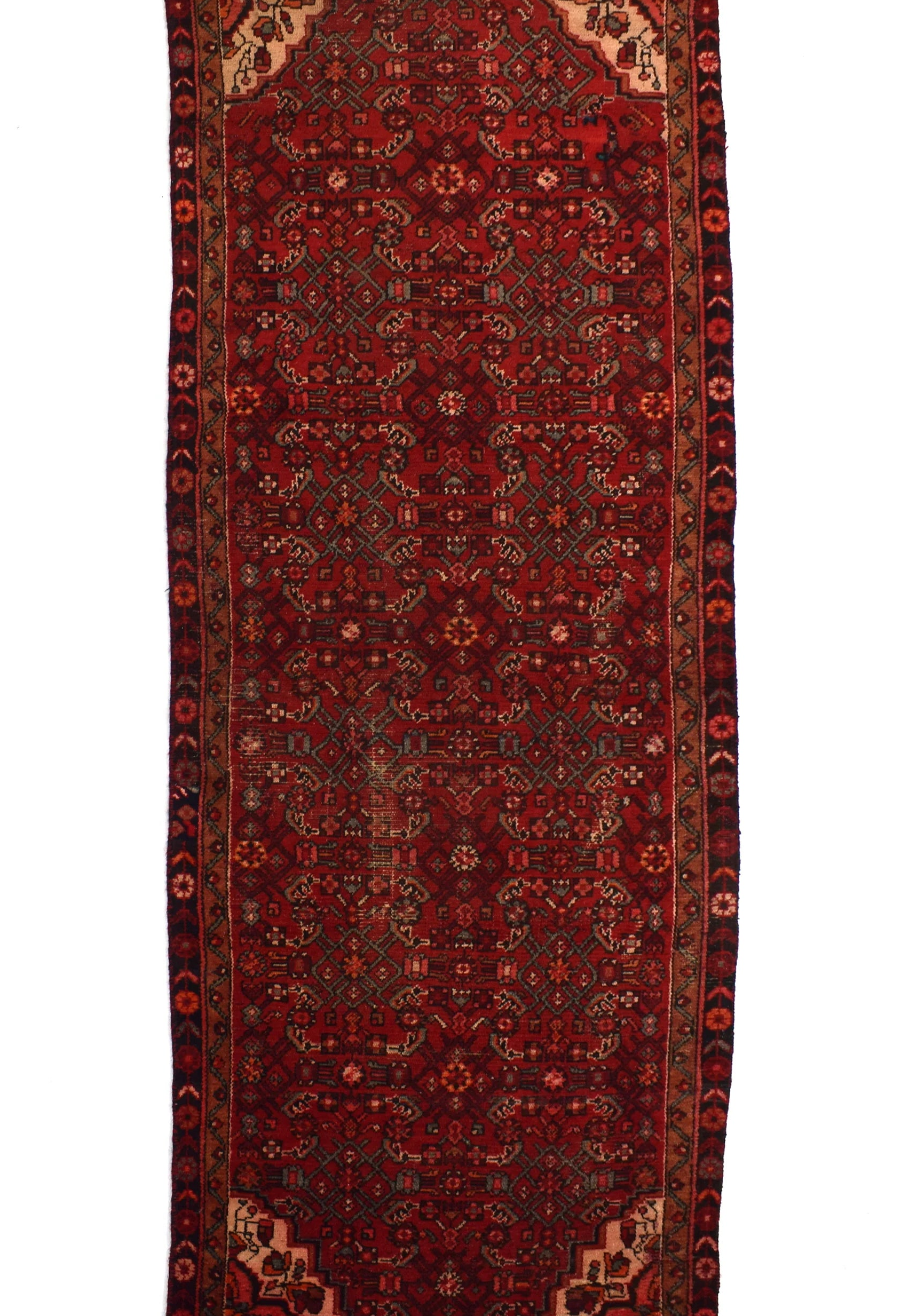 A traditional long runner rug with a deep red field, intricate geometric and floral motifs in black, beige, and rust, and a dark border.