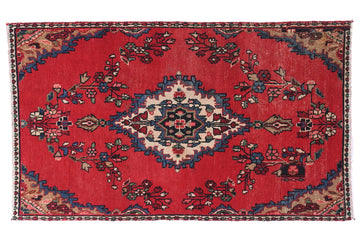 Decorative red rug with intricate patterns on a white background