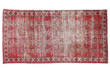 Red and beige patterned rug on a white background