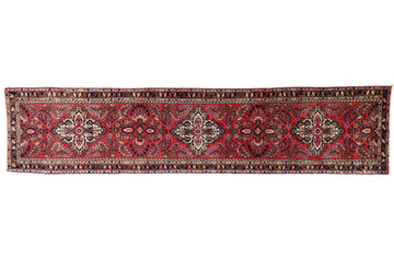 Long, narrow red and brown patterned rug on a white background