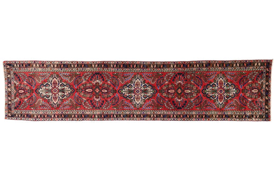 Long, narrow red and brown patterned rug on a white background